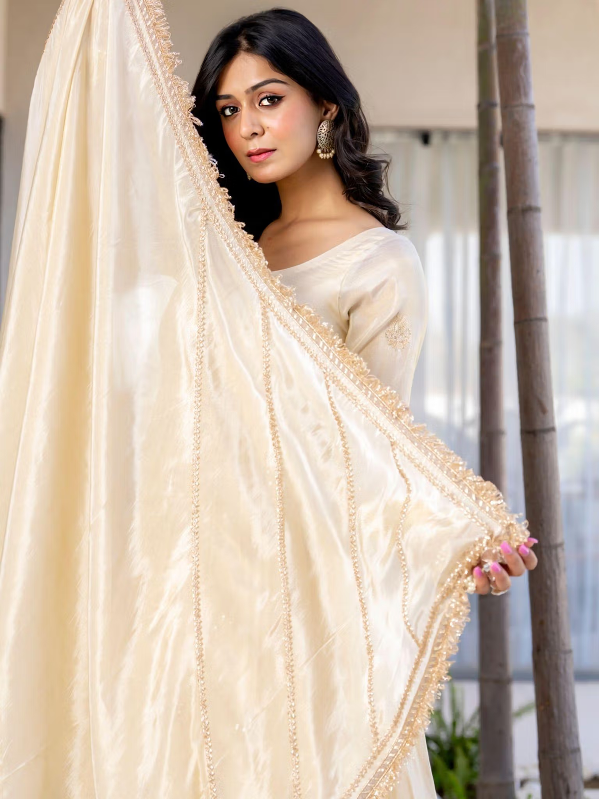 Aromie three piece Kurtha in cream with embellished dupatta held by model for product listing bright red floral co-ord set