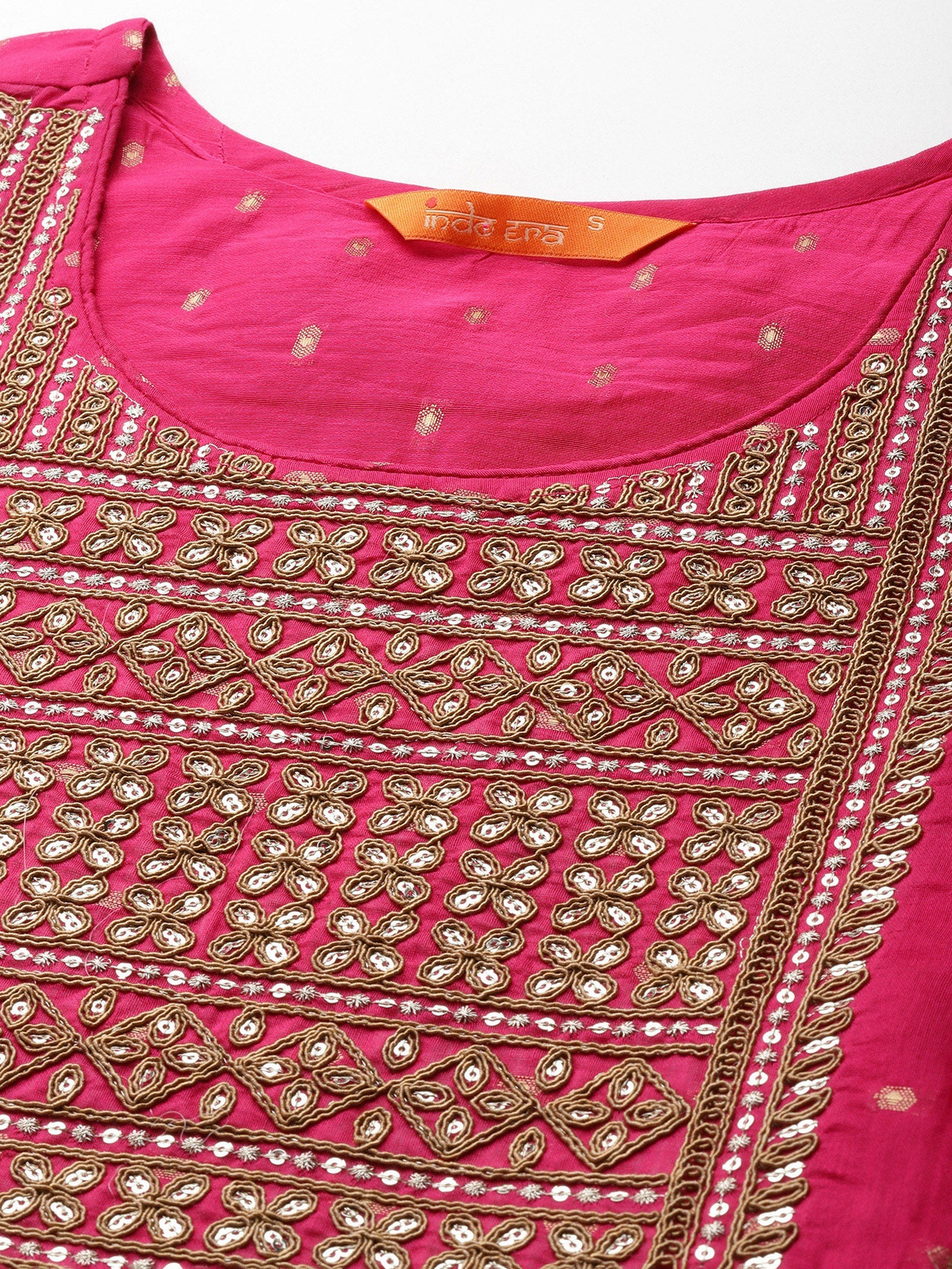 A close-up of a bright pink kurta featuring intricate gold and silver mirror work embroidery and beadwork around the neckline and front panel.