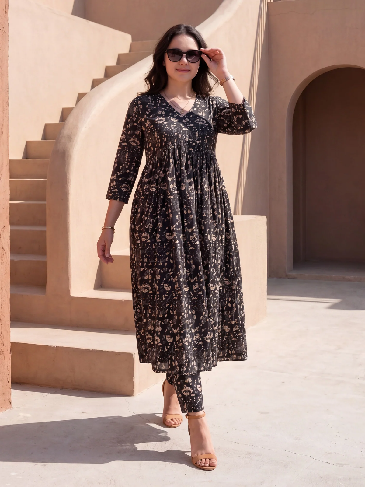 Woman in a black floral dress standing in front of a beige architectural background