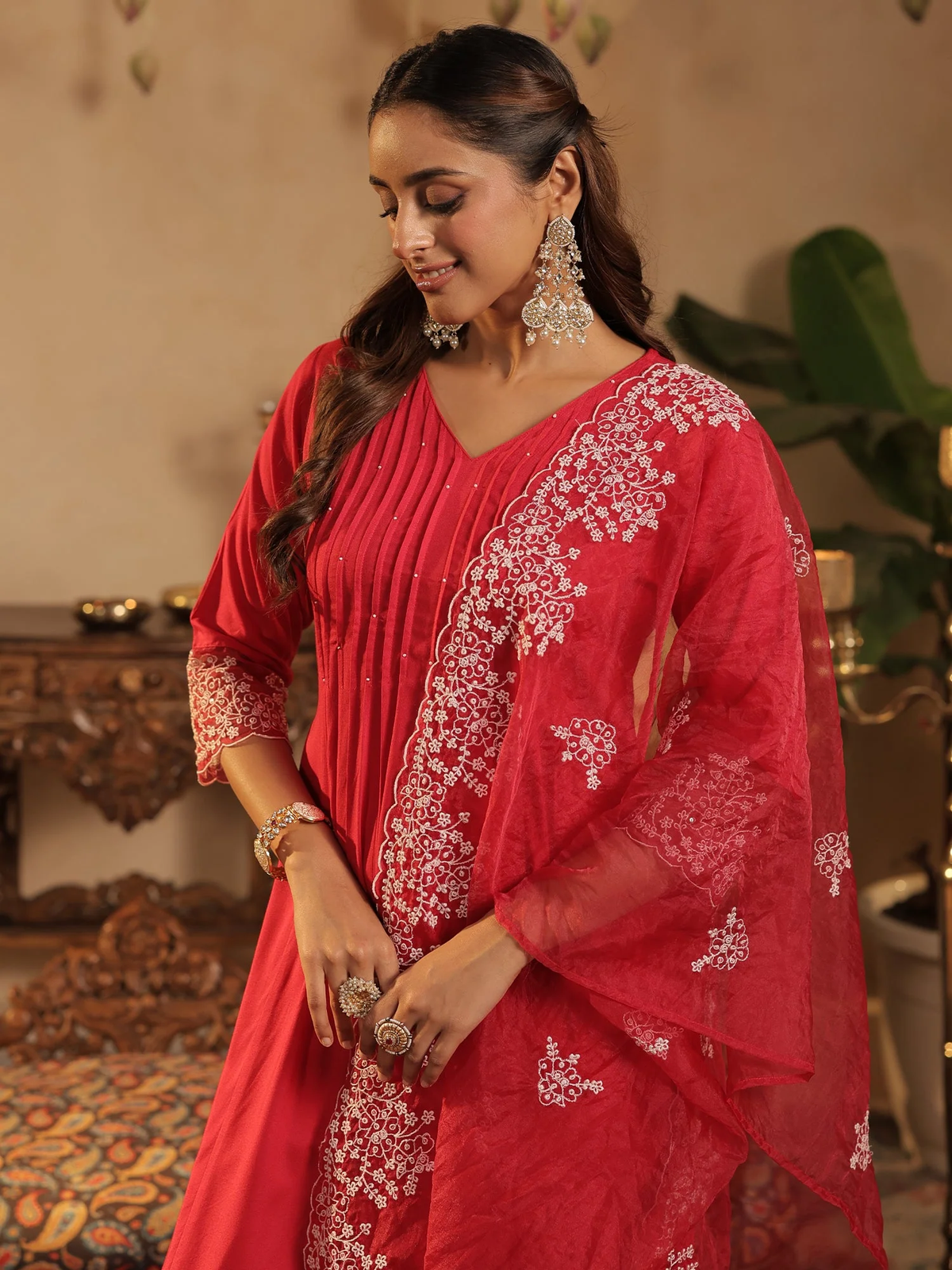 Woman wearing a red embroidered traditional outfit in an indoor setting.
