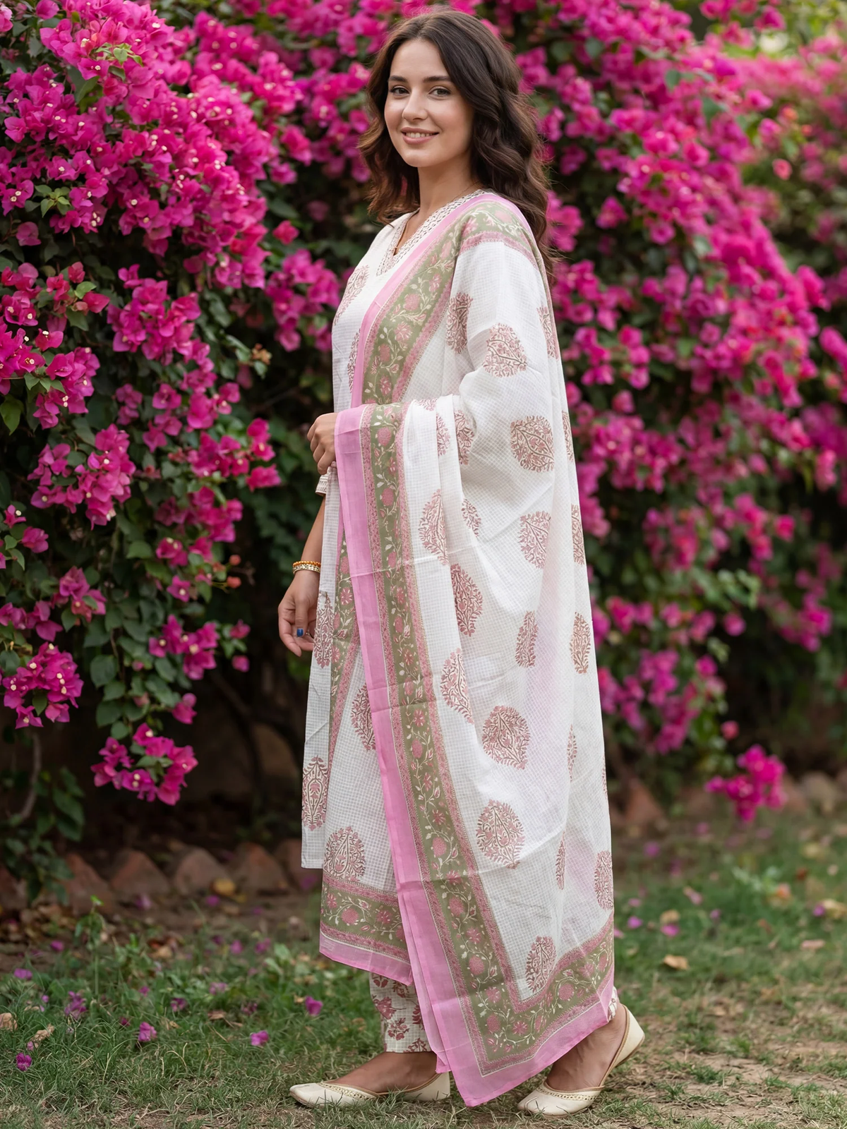 Woman in a white and pink traditional outfit standing in front of pink flowers