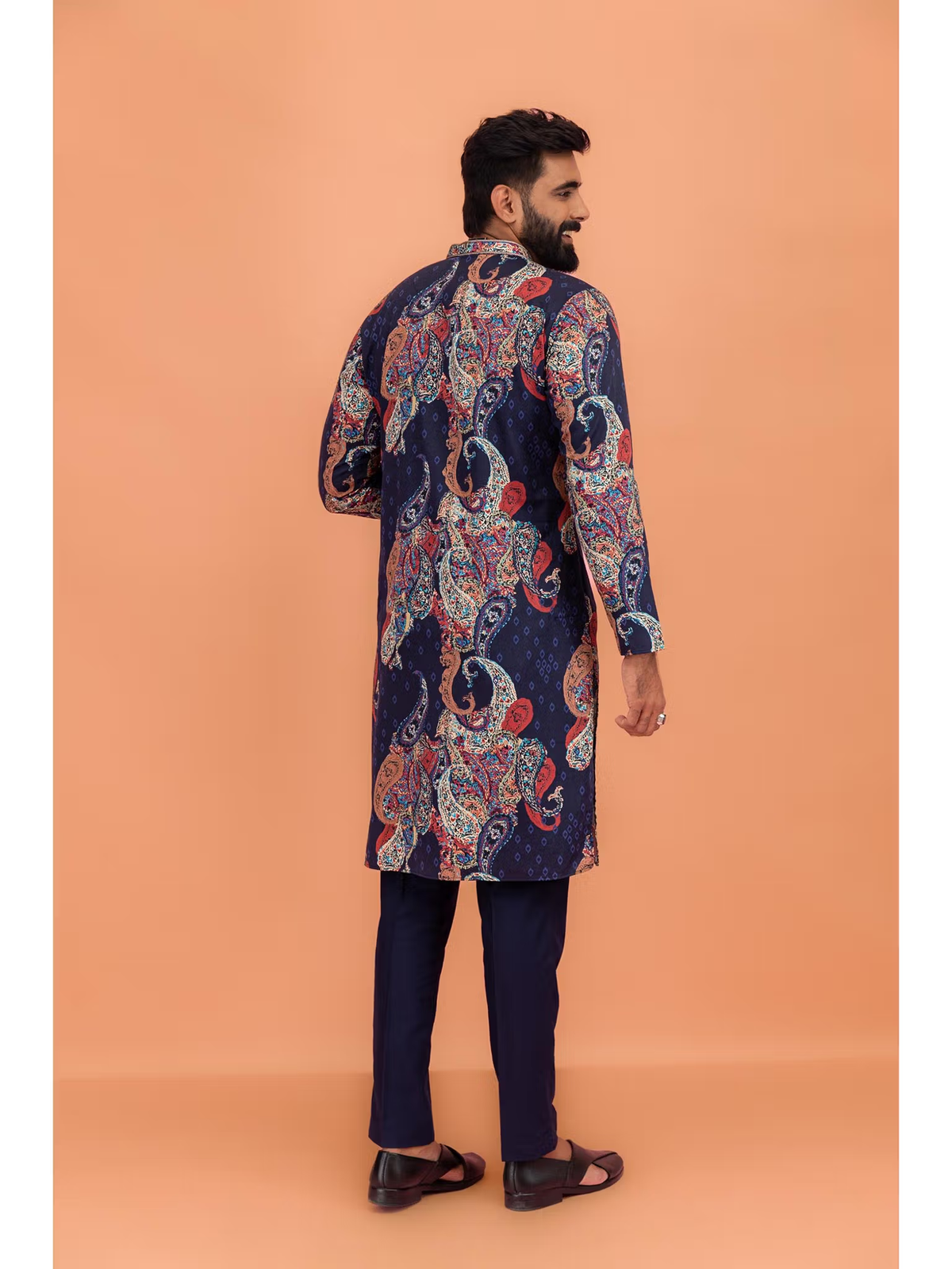 Man wearing men's black printed kurta Canada with colorful paisley print back view and navy pants