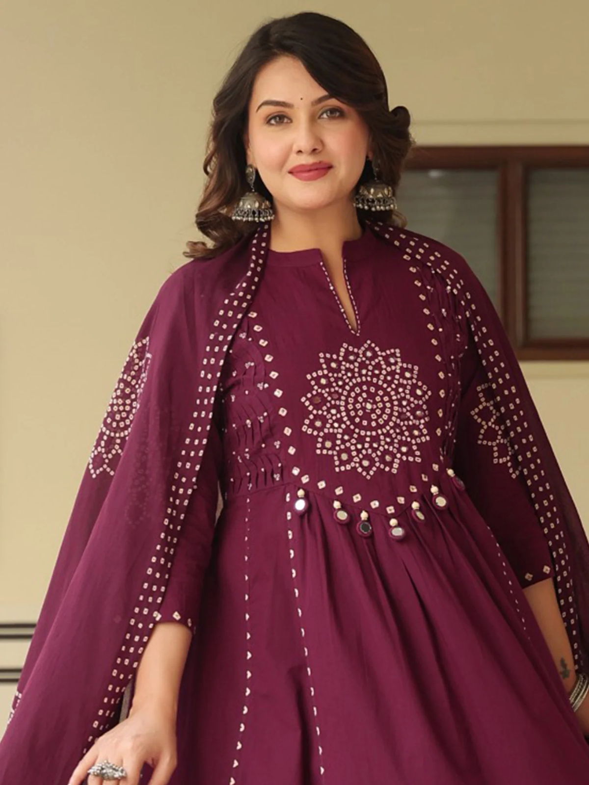 Woman wearing a maroon dress with intricate beadwork indoors.