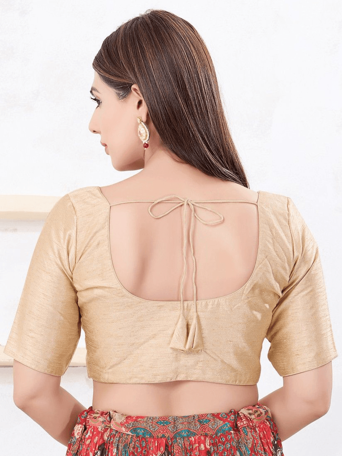 Woman wearing a beige blouse with a cut-out back design on a white background