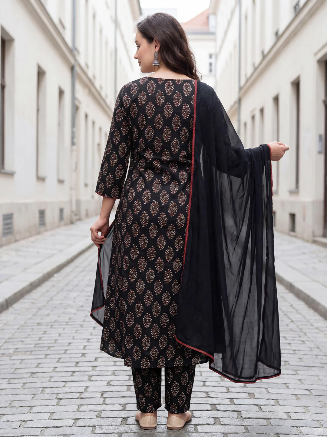 Woman in a black and patterned outfit walking down a street.