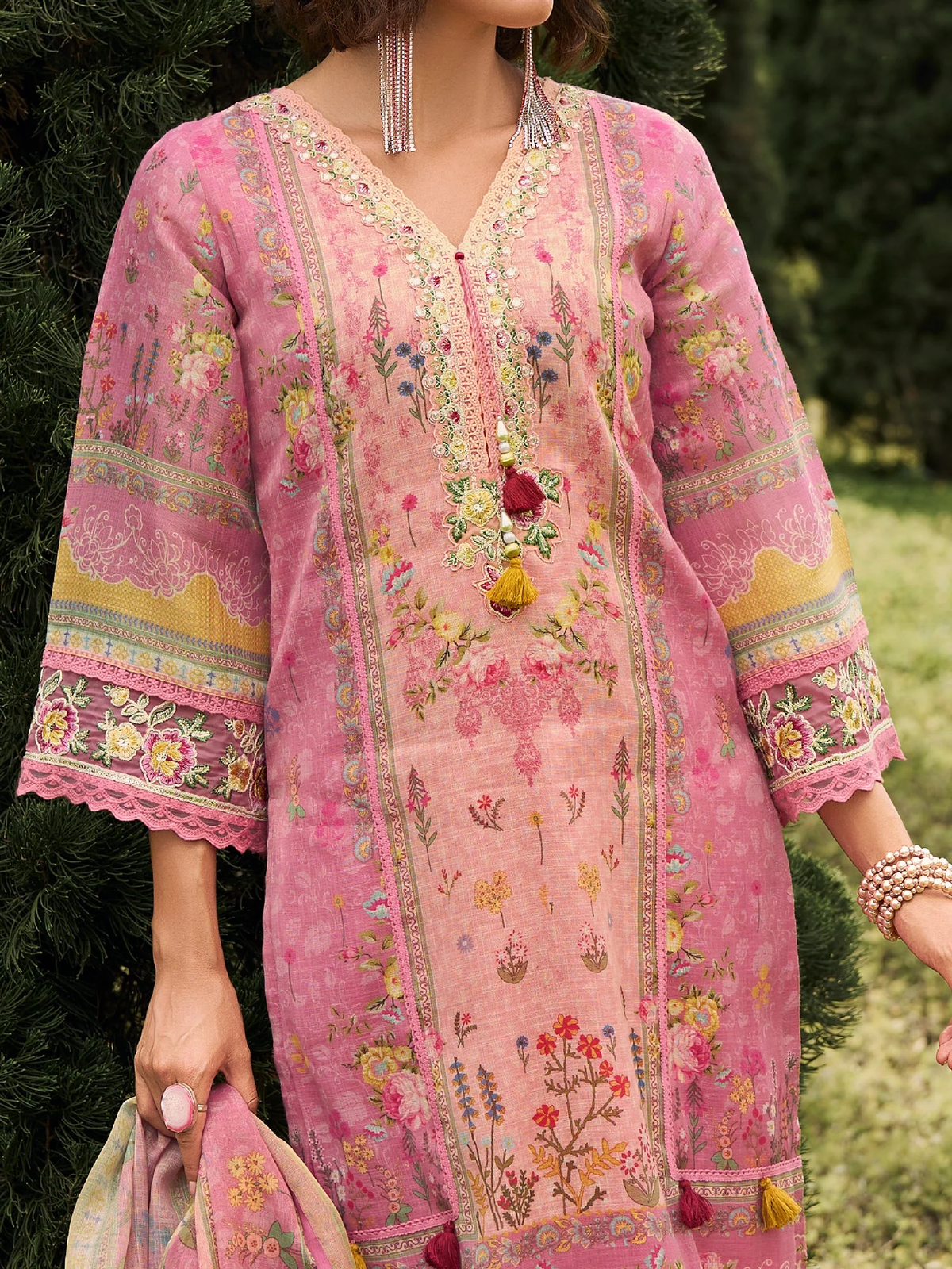 Pink embroidered traditional outfit with floral patterns in a natural setting