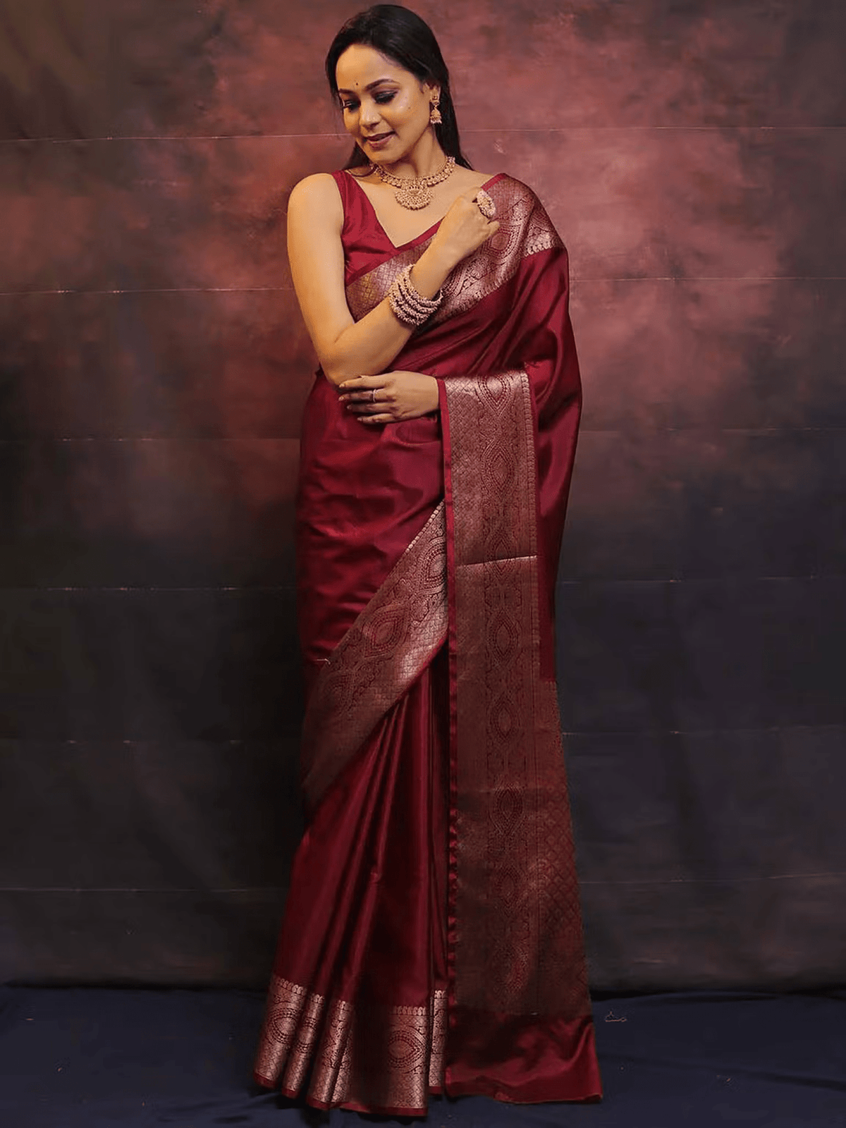 Aromie elegant festive saree set in deep maroon with intricate golden border design worn by a woman