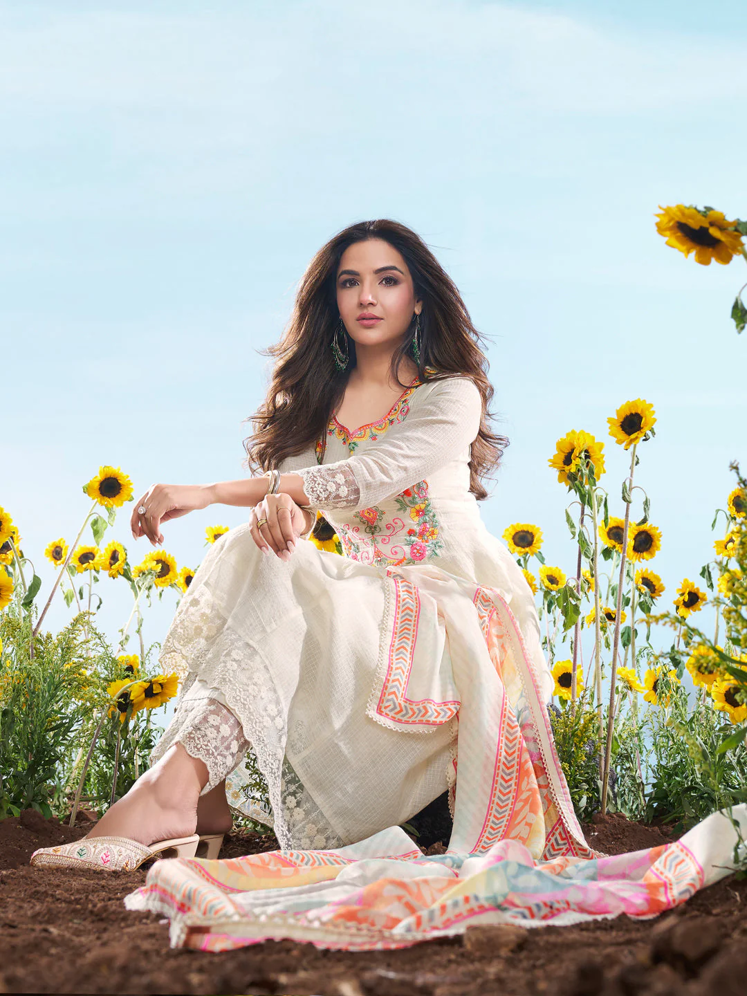 Elegant three piece kurta set in white with floral embroidery, perfect for weddings. View from front in a sunny outdoor setting.