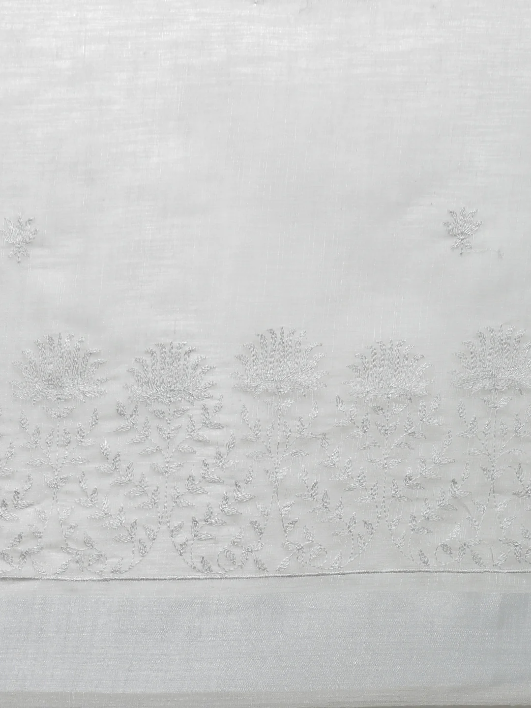Embroidered saree in soft white silk featuring intricate floral designs, ideal for weddings or festive occasions