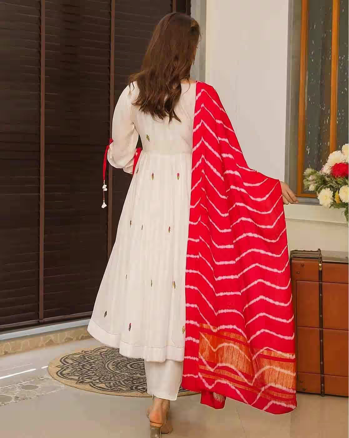 Aromie floral cotton kurta set back view model wearing white ankle length kurta with colorful motifs and red striped dupatta