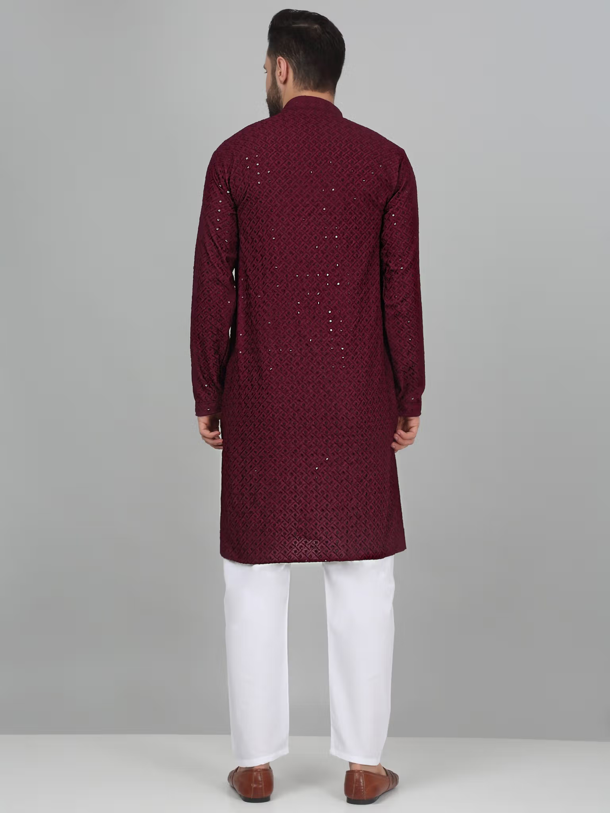 Back view of model wearing men's burgundy embroidered kurta set with white churidar pants and brown leather shoes