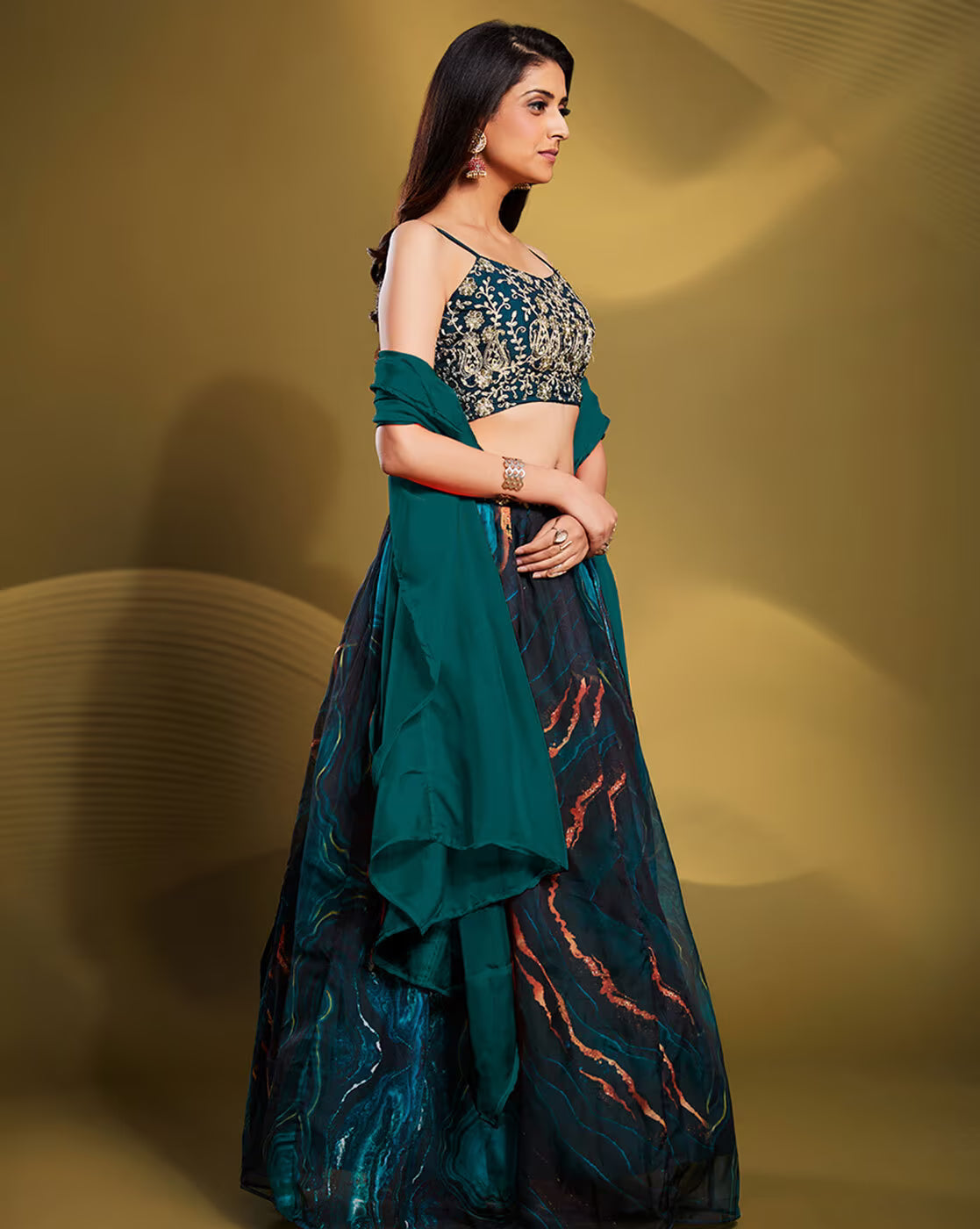 Woman wearing emerald and navy embellished lehenga choli set Canada with gold embroidered crop blouse and flowing dupatta