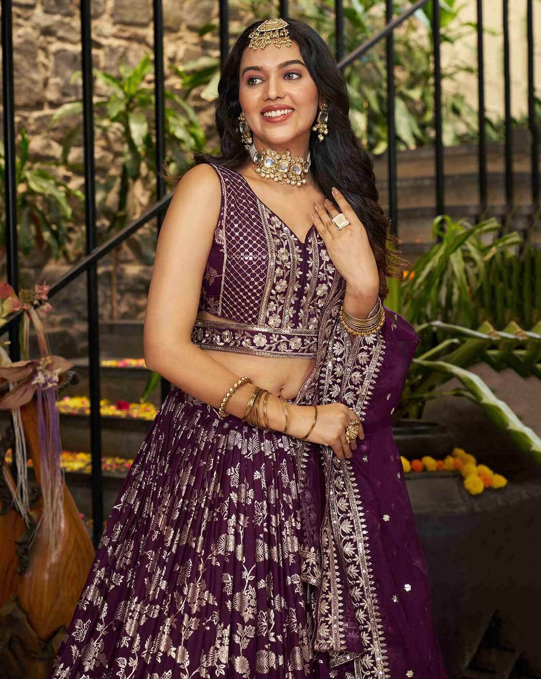Model wearing a deep purple embroidered lehenga choli set Canada with matching dupatta and gold jewelry