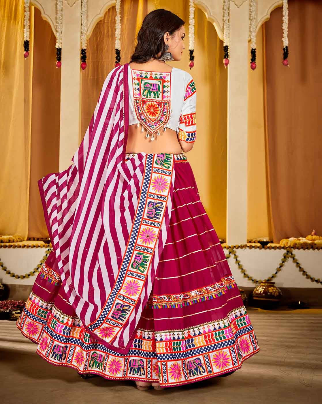Back view of model wearing magenta embroidered lehenga choli set Canada with striped dupatta and vibrant tribal embroidery