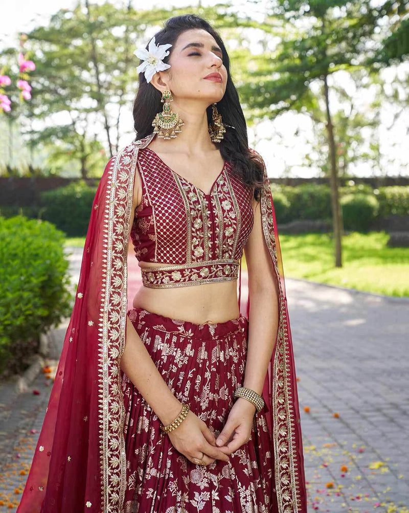 Model wearing maroon embroidered lehenga choli set Canada with gold threadwork dupatta and statement earrings