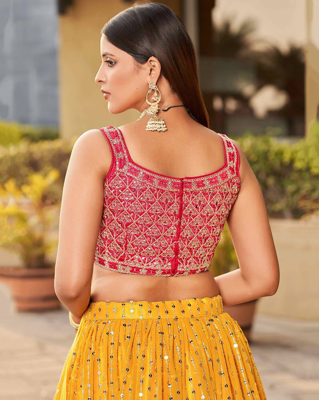 Back view of model in pink embroidered choli blouse and yellow lehenga with jhumka earrings embroidered lehenga choli set Canada
