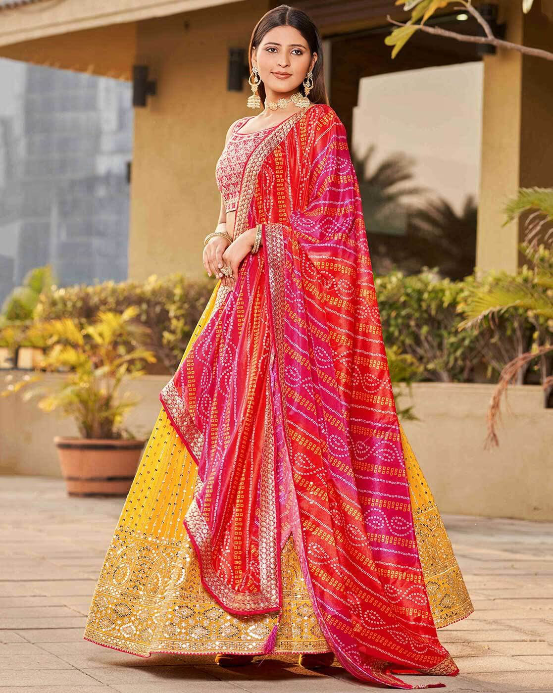 Model in colorful embroidered lehenga choli set Canada yellow gold skirt with heavy mirror embroidery and pink bandhani dupatta