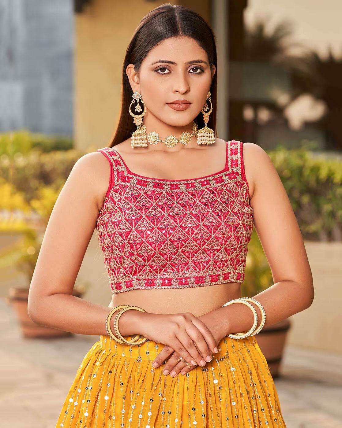 Model wearing embroidered lehenga choli set Canada pink embroidered crop blouse with diamond pattern and yellow sequined skirt
