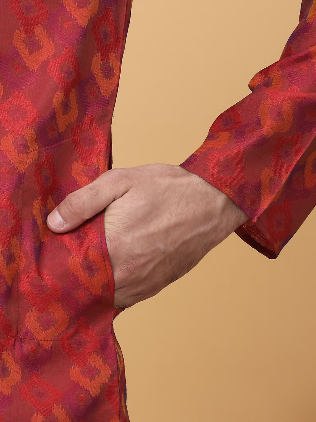 men maroon silk kurta pajama set closeup showing patterned maroon kurta sleeve and hand in side pocket