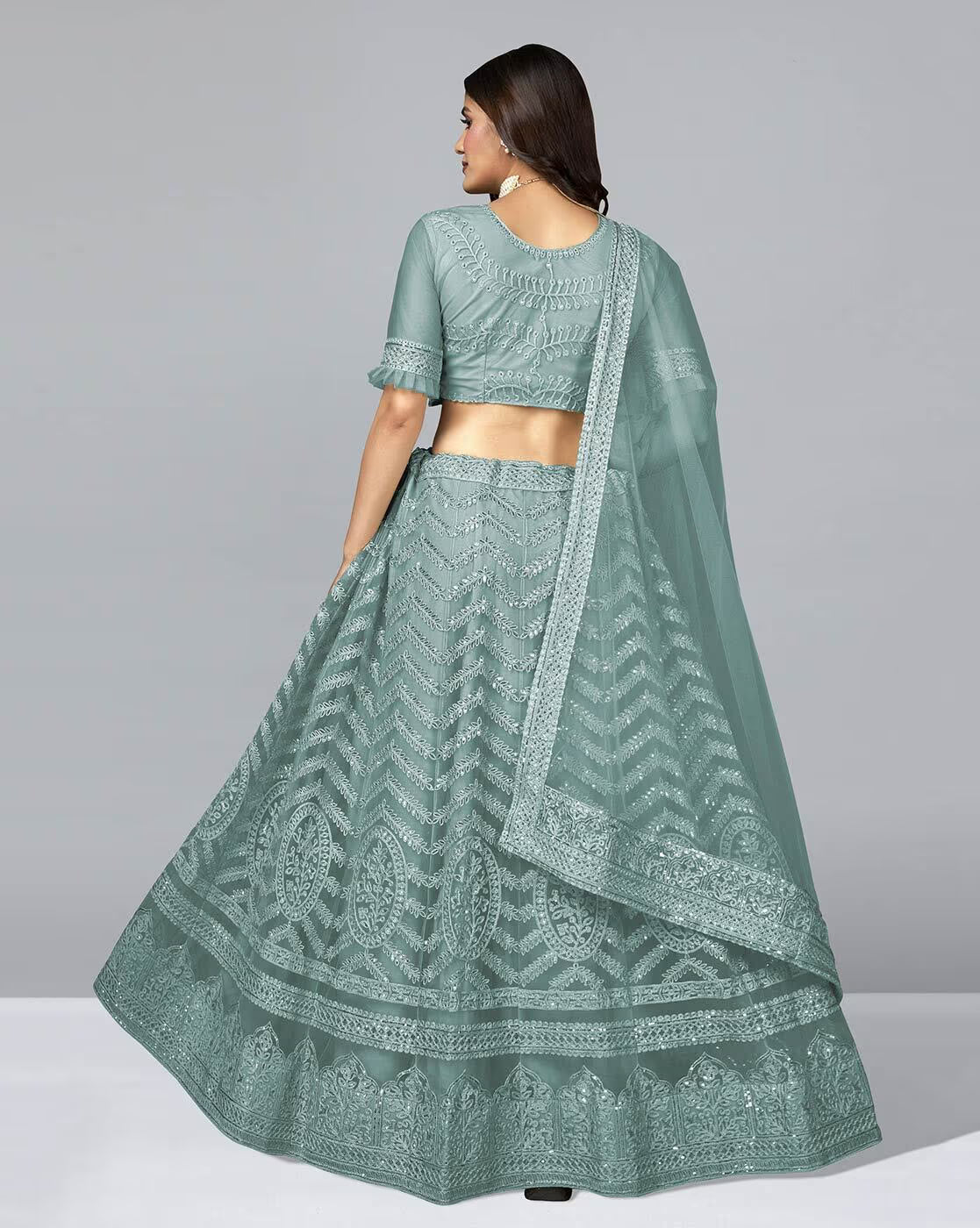Back view of model wearing seafoam green Embellished A-Line Lehenga Choli Set with embroidered skirt and dupatta