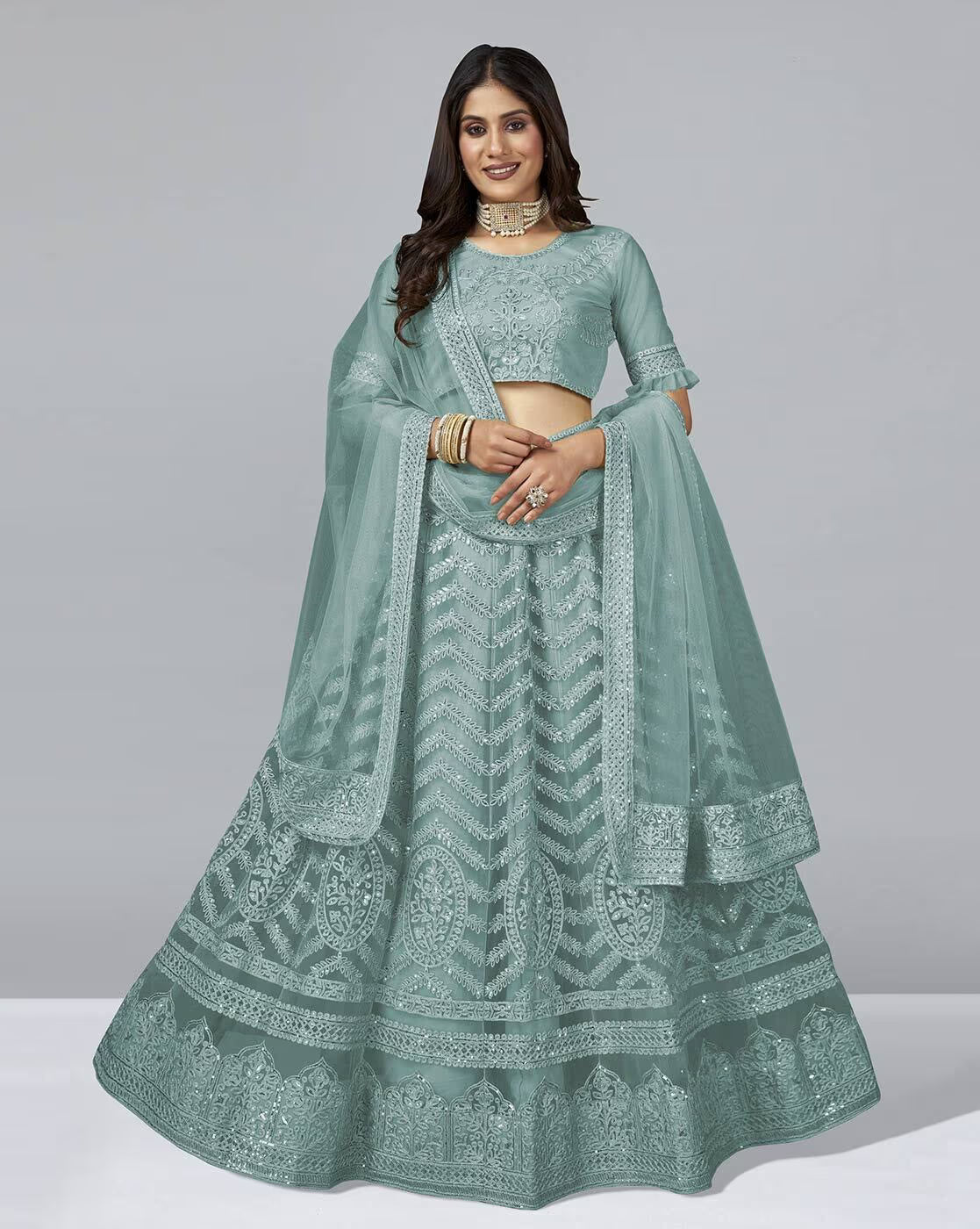 Model wearing a sage green Embellished A-Line Lehenga Choli Set with intricate embroidery and matching dupatta
