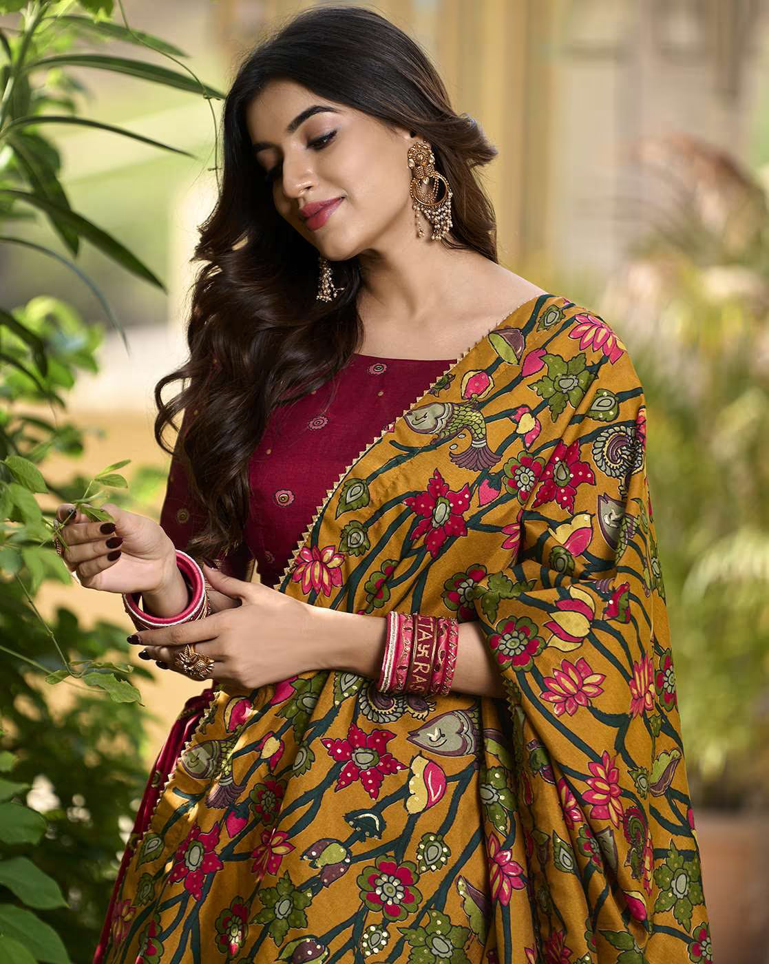 AROMIE woman modeling mustard floral lehenga with maroon blouse and dupatta wearing statement earrings Lehenga Choli Set Canada