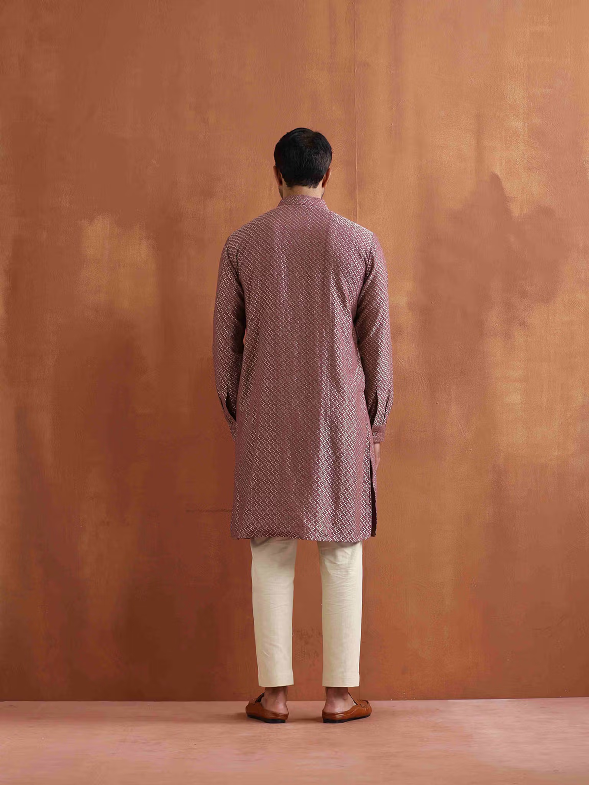 Back view of model wearing men's purple cotton kurta with patterned print cream trousers and brown sandals
