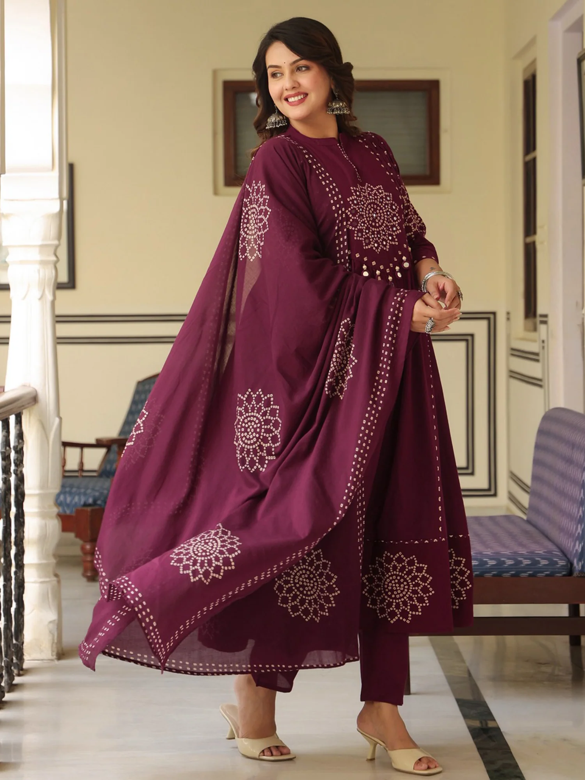 Woman wearing a purple embroidered traditional outfit in an indoor setting.