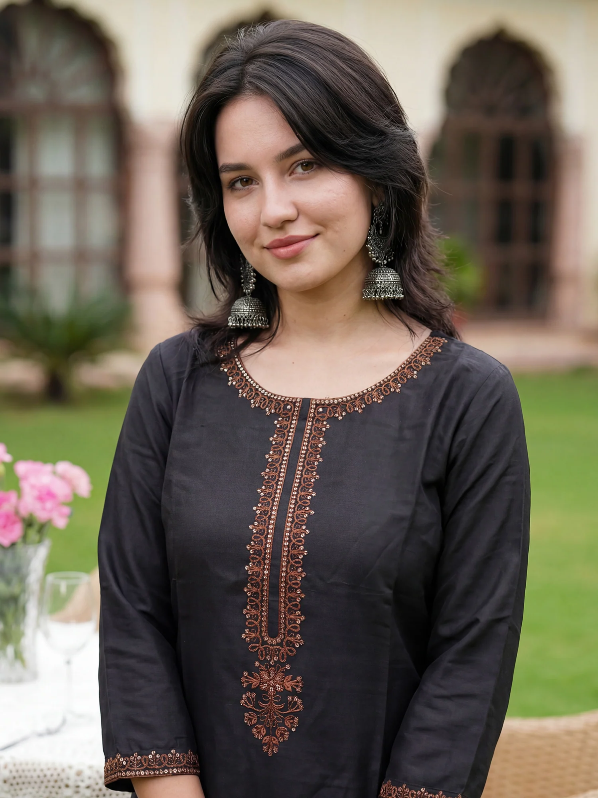 Woman wearing a black embroidered dress outdoors with blurred background
