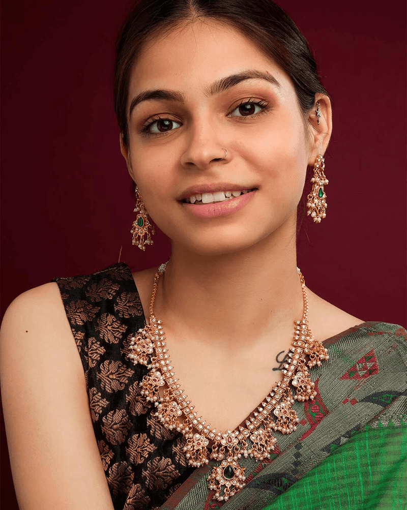 Aromie model wearing vintage gold-plated necklace set with intricate pearl floral motifs and matching earrings
