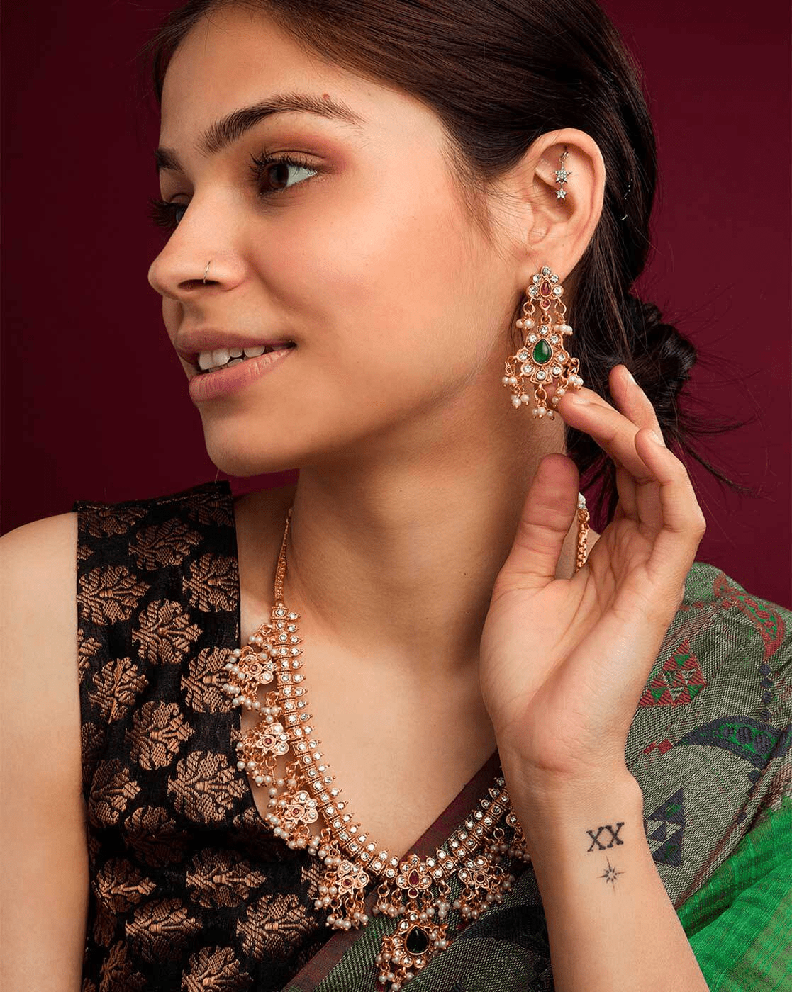 Aromie model wearing vintage gold-plated necklace set with matching green stone earrings on saree
