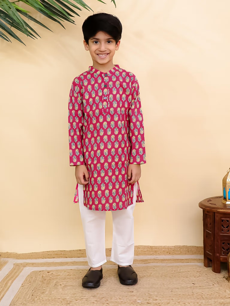 Smiling boy modeling red printed kurta pyjama set Canada paired with white pants and black shoes