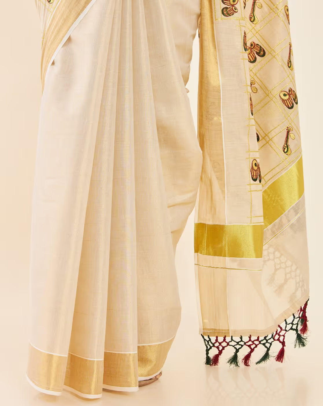 Elegant white Kasavu Saree Canada with intricate golden embroidery and colorful tassels, perfect for festive occasions.