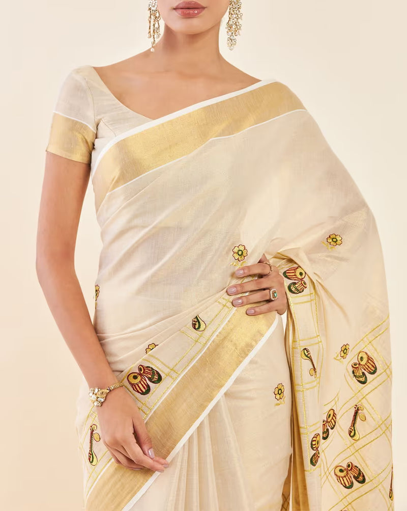 Elegant cream Kasavu Saree from aromie with gold border and detailed floral embroidery, perfect for festive occasions
