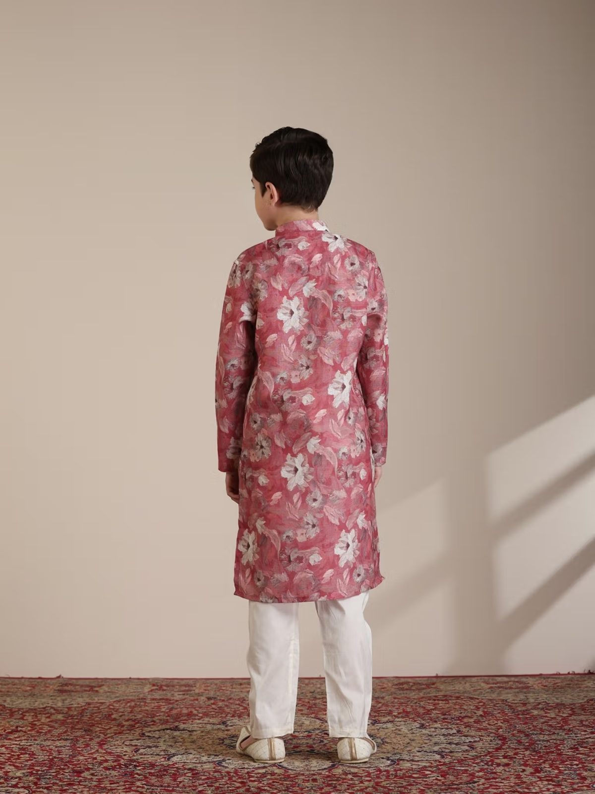 Young boy seen from back wearing floral boys pink kurta pyjama set Canada with white pyjama pants on rug