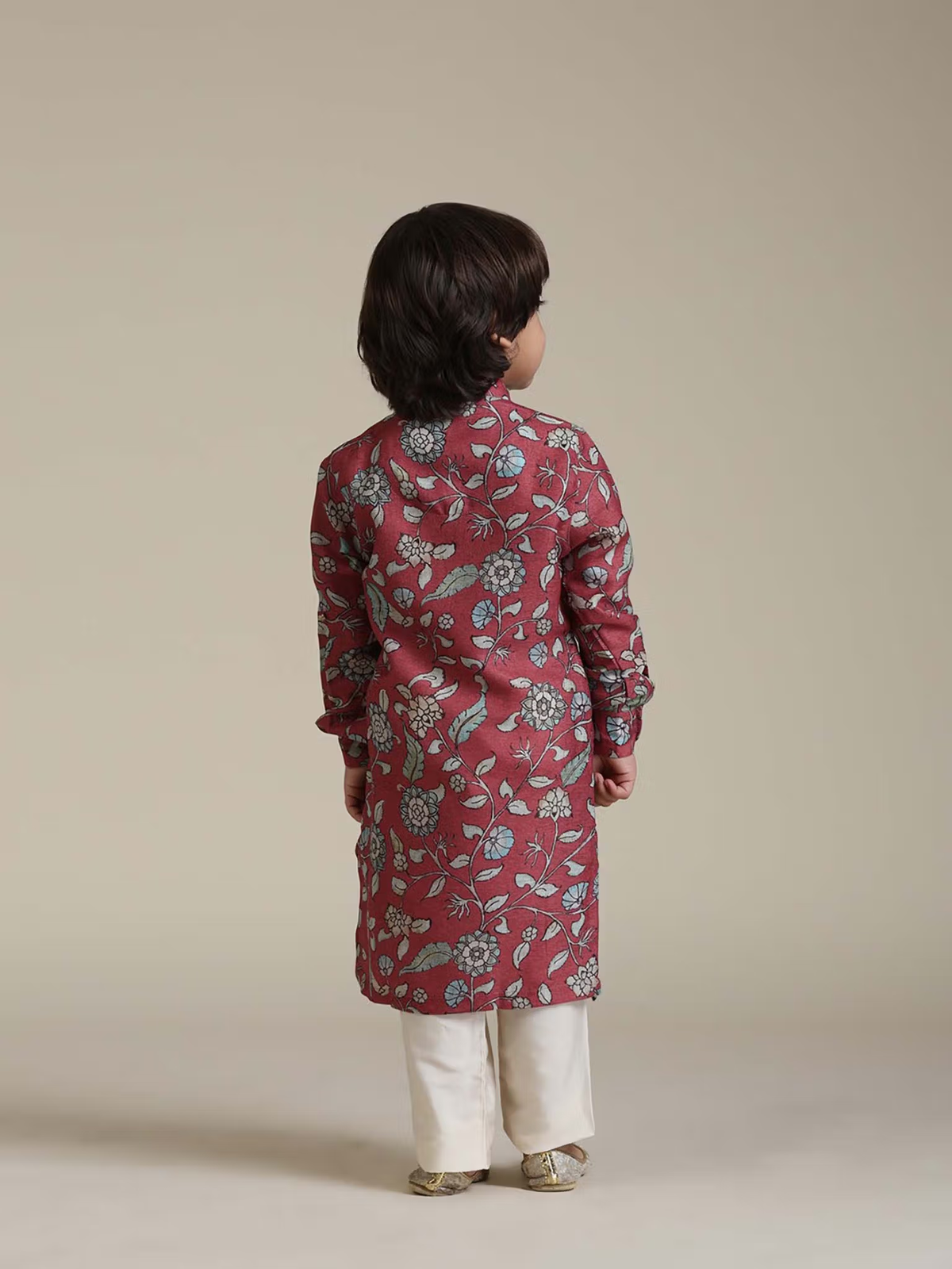 Young boy seen from back wearing kids rust floral kurta pyjama set with white trousers and traditional shoes