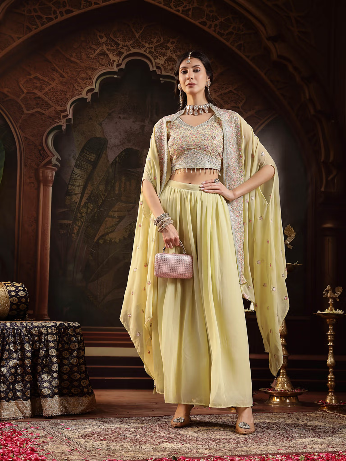 Model wearing a lime green embroidered co-ord set with a stylish cape and elegant accessories