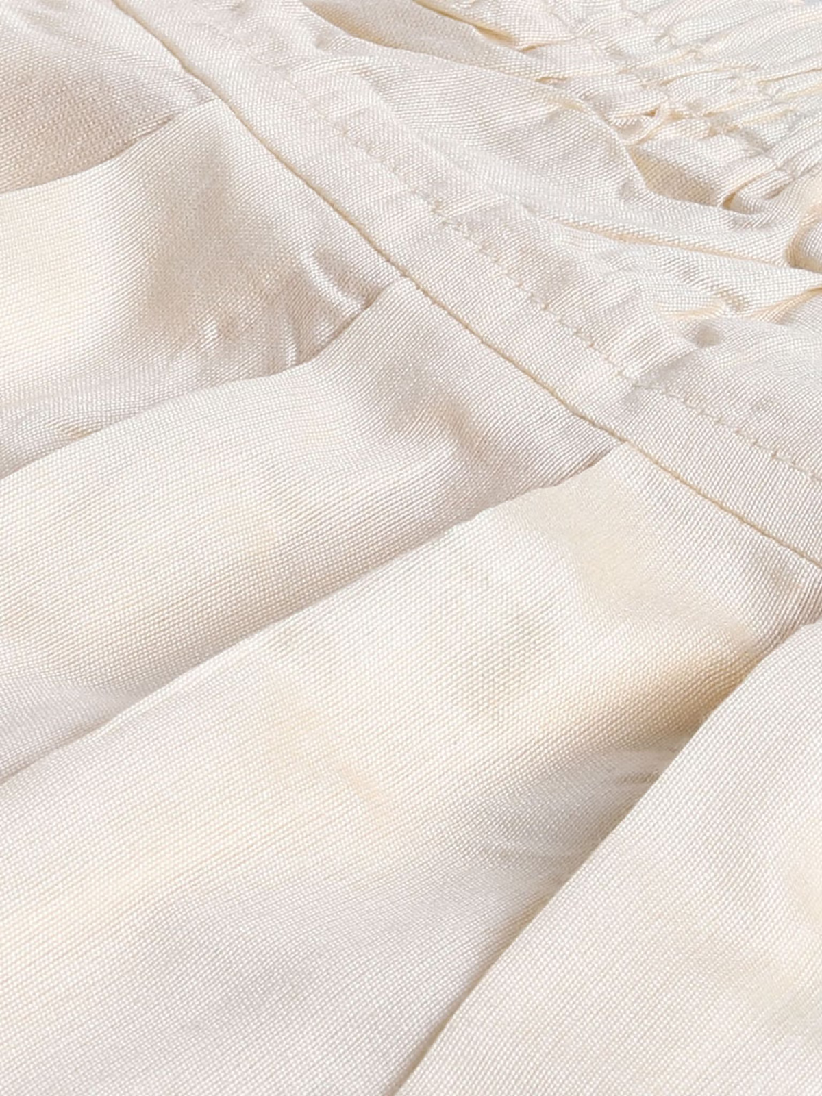 Close up of cream cotton infant boys kurta patiala set showing pleats smocked waist and stitched seam detail
