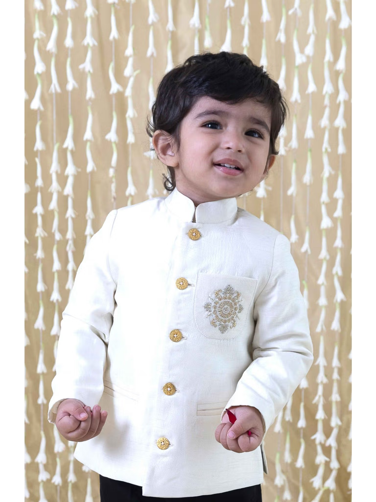 cream bandhgala for baby boys worn by toddler with gold buttons and embroidered pocket in festive setting