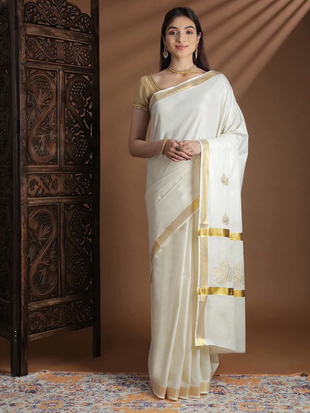 Elegant white onam saree with gold border and floral embroidery, perfect for festive celebrations