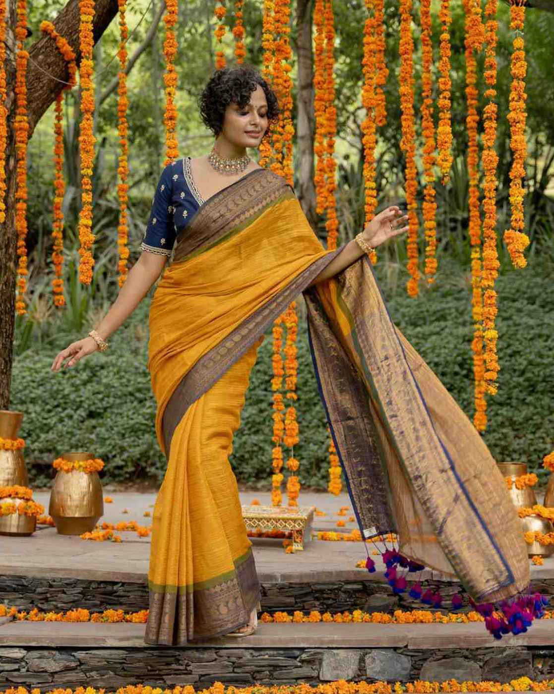 Aromie elegant organza saree with stone work in vibrant yellow, styled with a blue blouse against floral backdrop