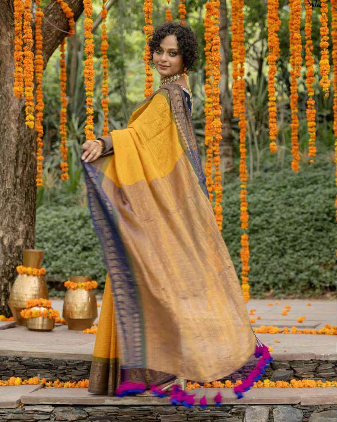 Elegant aromie organza saree with stone work draped stylishly outdoors with vibrant marigold decor