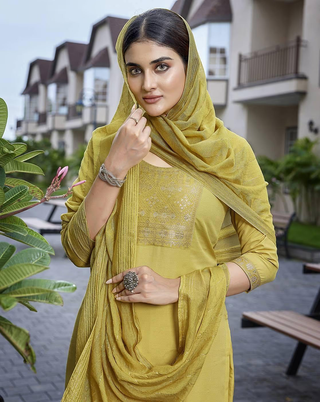 Elegant model wearing a mustard three piece kurta set with scarf in a serene outdoor setting