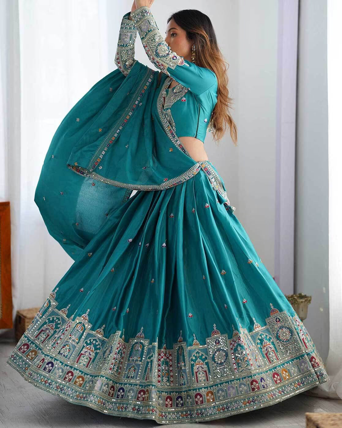 Model wearing teal embroidered lehenga choli set Canada with ornate mirror and threadwork border and matching dupatta
