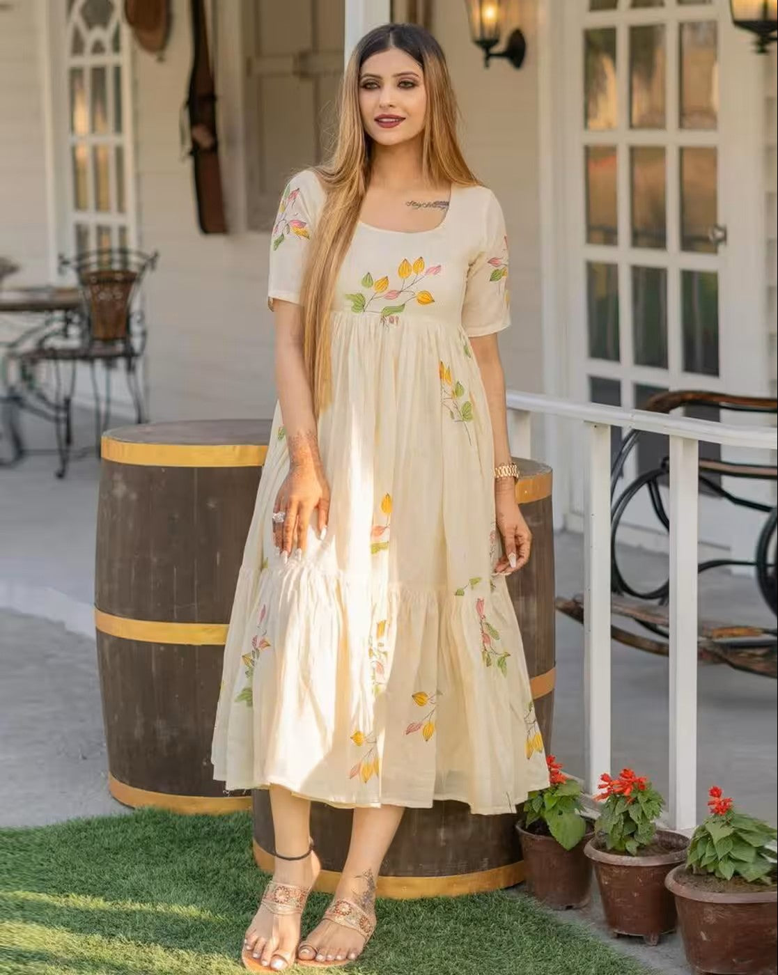 Woman wearing aromie rust orange mini dress with floral patterns standing outdoors near barrels and potted plants