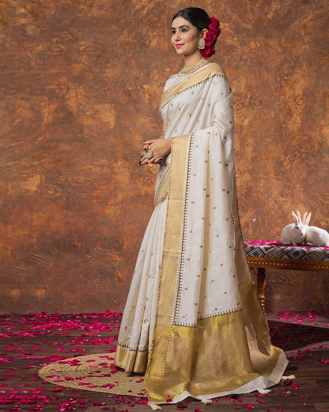 Aromie sequin embellished saree online in white and gold worn by a woman with traditional jewelry and floral hair accessories