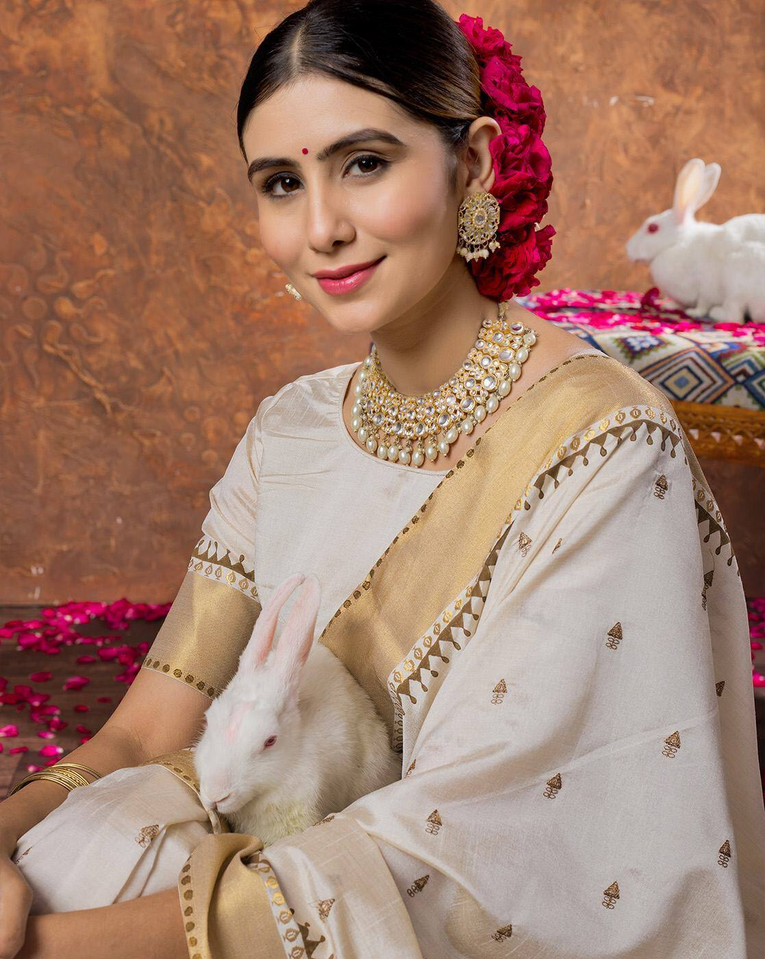Aromie sequin embellished saree online cream and gold saree worn by woman holding a white rabbit