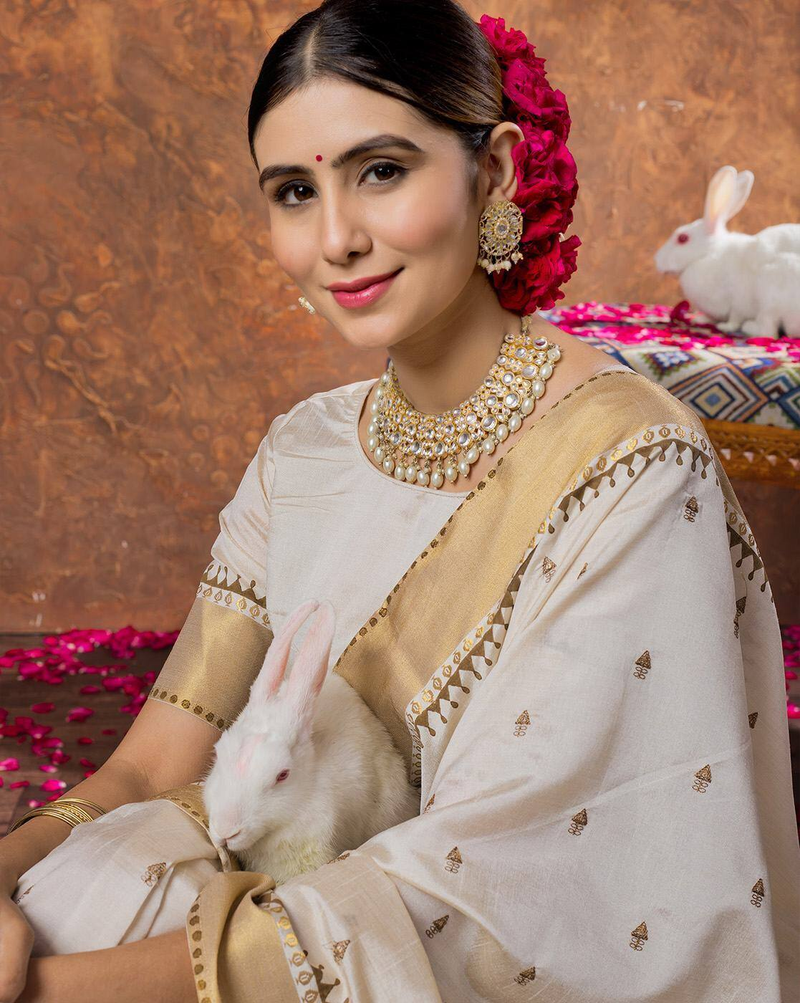 Aromie sequin embellished saree online cream and gold saree worn by woman holding a white rabbit