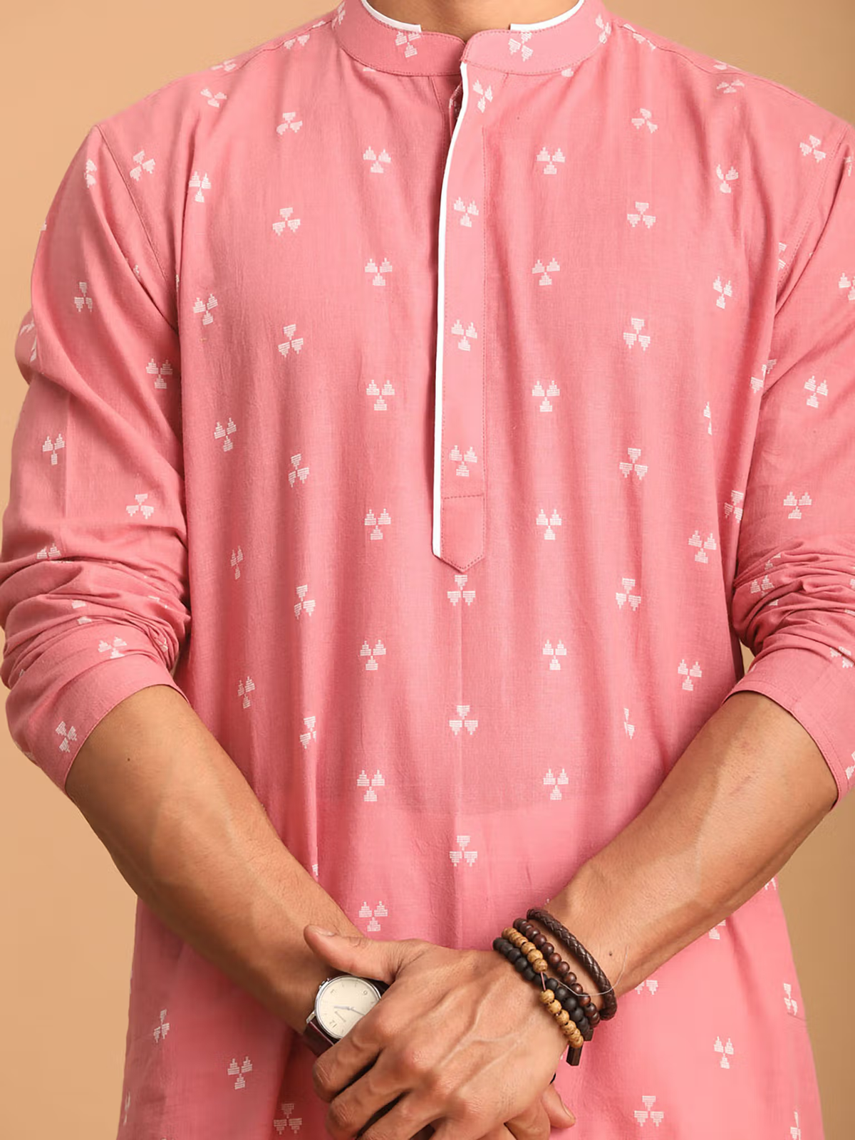 mens pink cotton kurta with small white motifs mandarin collar side placket rolled sleeves styled with watch and bracelets