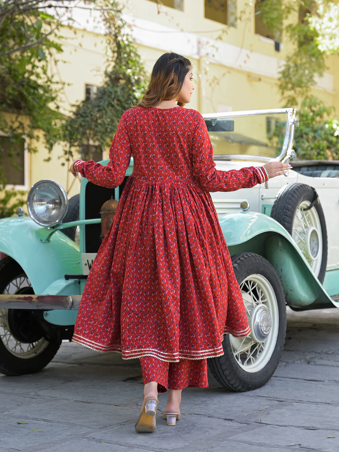 Elegant back view of a woman in a red Anarkali kurta trouser set with dupatta, styled with a vintage car